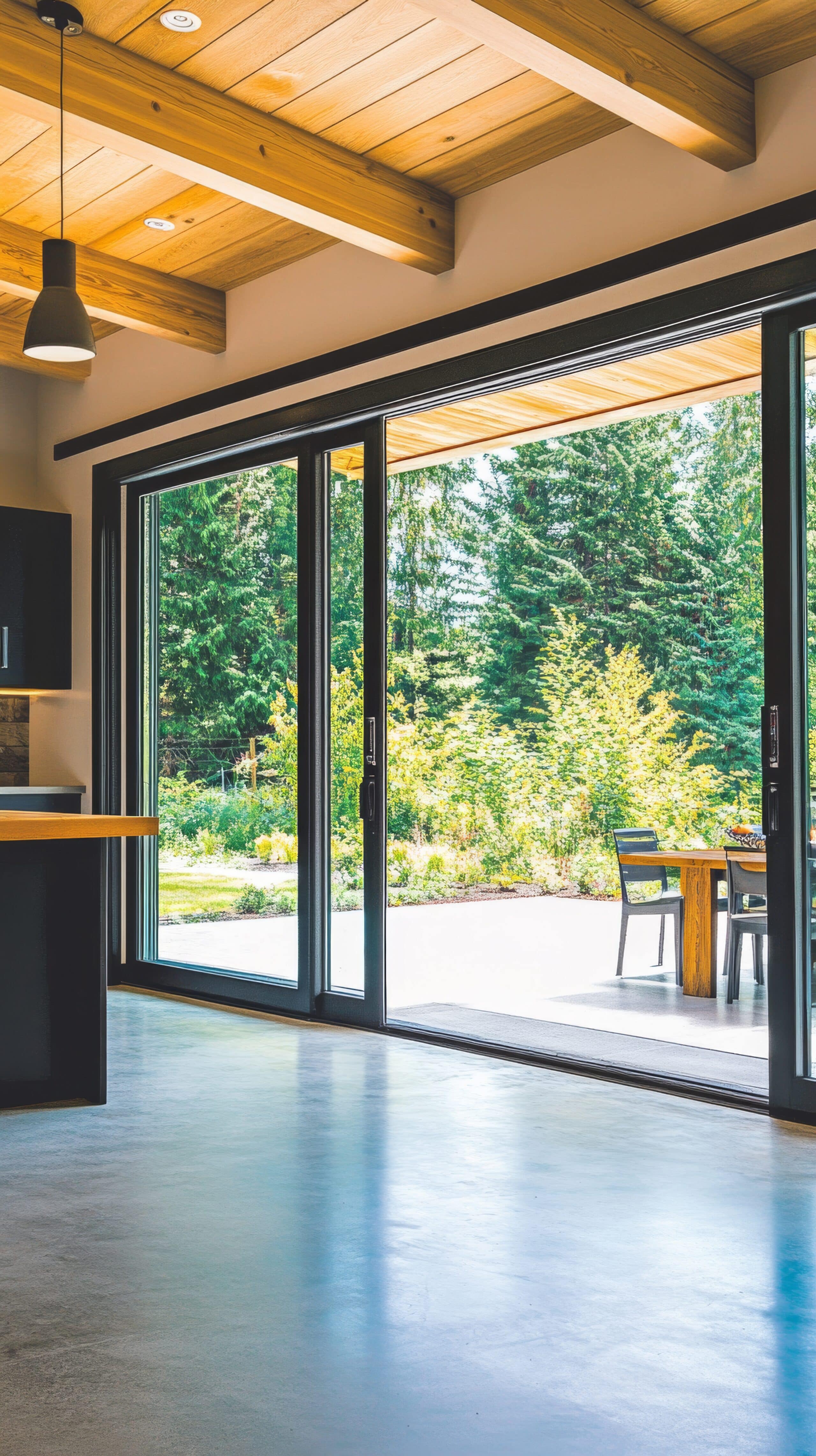 A spacious and modern open-concept living area highlighted by large windows that invite natural light and views of the lush outdoor landscape.