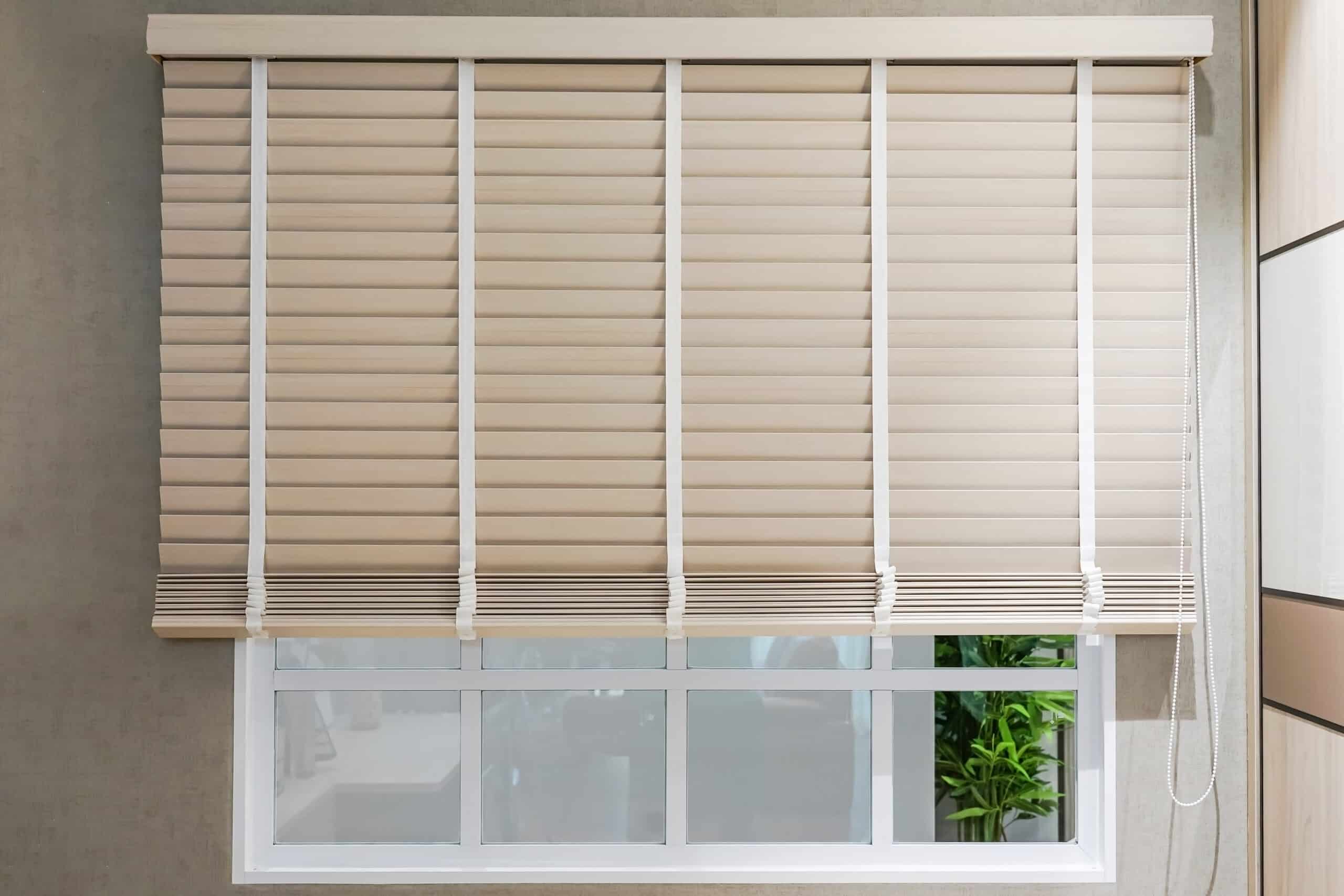 Sun-protection jalousie of white color on the window in a bright sunny day