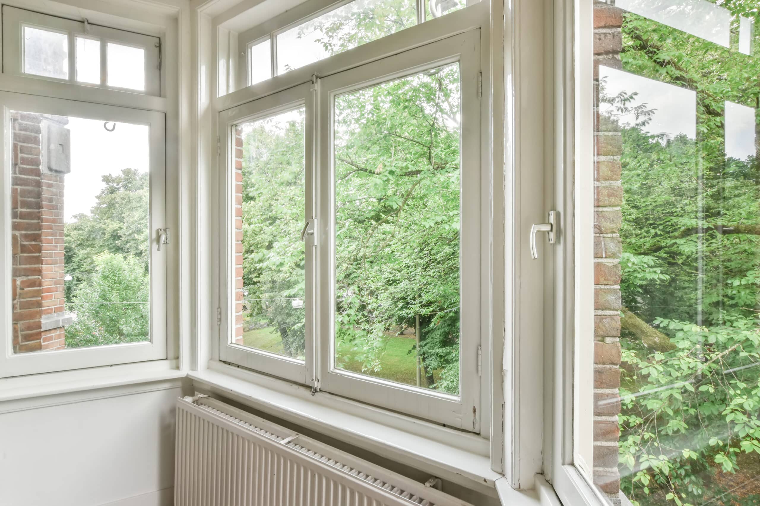 Big white windows of a living room facing the yard